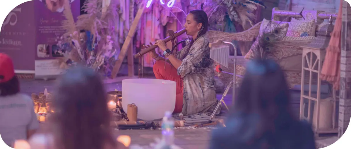 A latin woman with braids and loose cloths playing a wooden flute