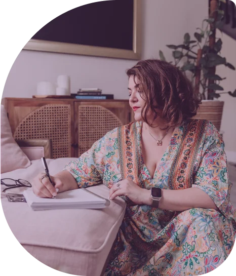 Mariel, a latin woman, with short brown hair and a floral dress, peacefully writing on a notebook